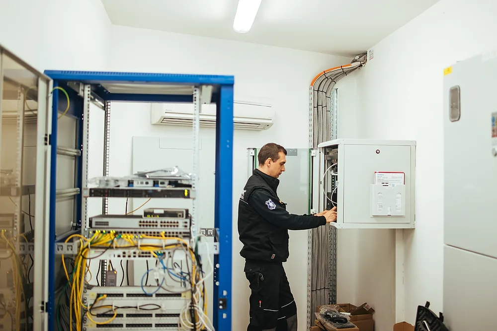 Tehničar Zaštite Jukić spaja instalaciju u razdjelnom ormaru pokraj komunikacijskog ormara s mrežnom opremom