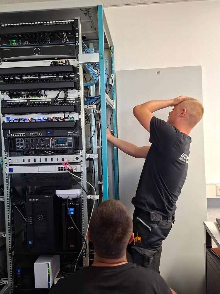 Dvojica tehničara Zaštite Jukić rade na komunikacijskom ormaru s mrežnom i serverskom opremom
