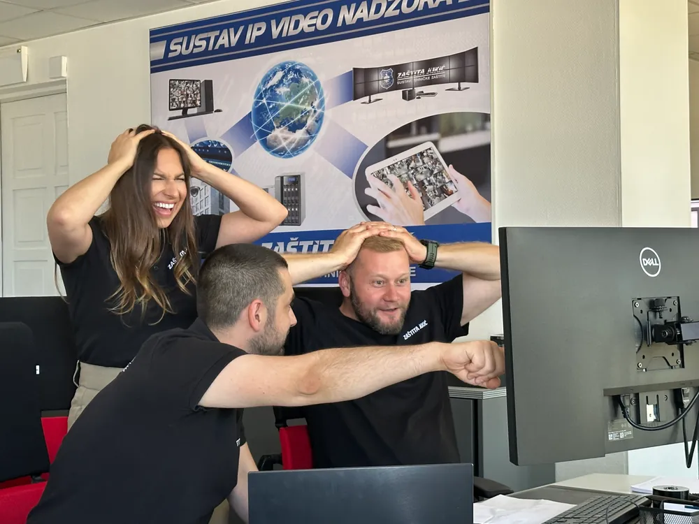 Troje djelatnika Zaštite Jukić u vedrom trenutku za radnim stolom, iza njih plakat o sustavu IP videonadzora