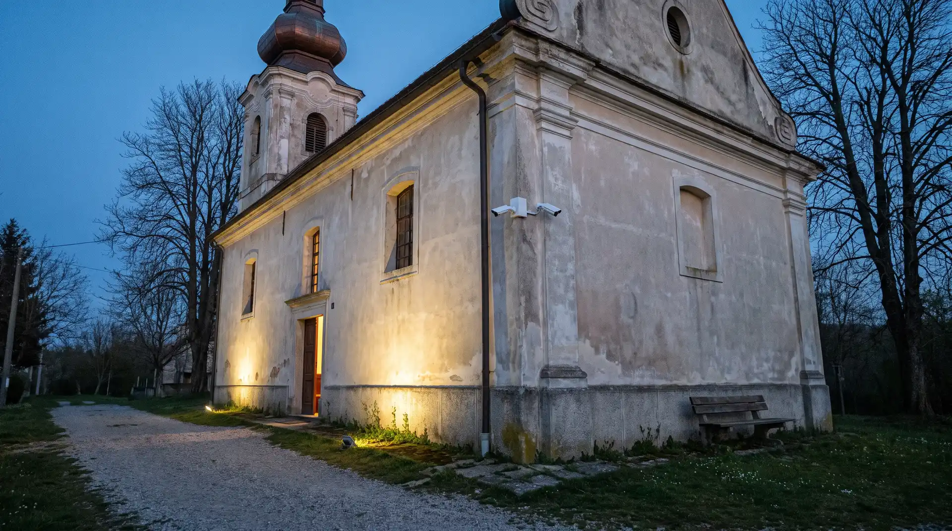 Seoska barokna crkva u sumrak s diskretnom kamerom videonadzora na uglu pročelja